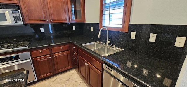 kitchen with sink, dark stone countertops, decorative backsplash, light tile patterned flooring, and appliances with stainless steel finishes