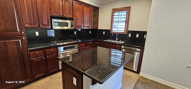 kitchen with decorative backsplash, appliances with stainless steel finishes, sink, light tile patterned floors, and a kitchen island