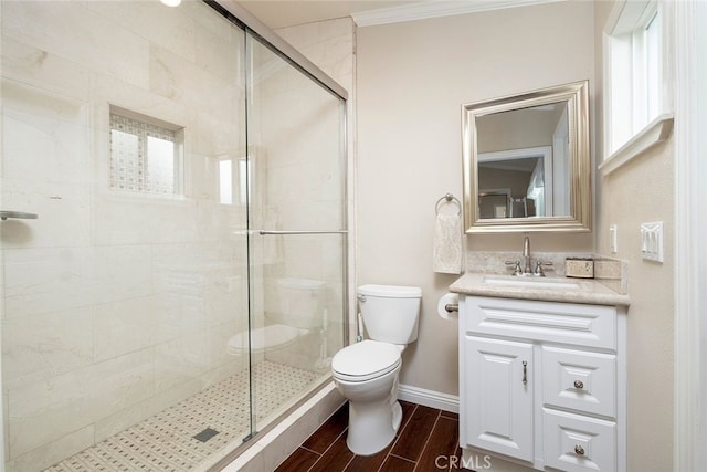 bathroom featuring vanity, toilet, a shower with shower door, and ornamental molding