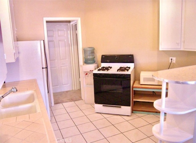 kitchen featuring white cabinets, white appliances, sink, and light tile patterned floors