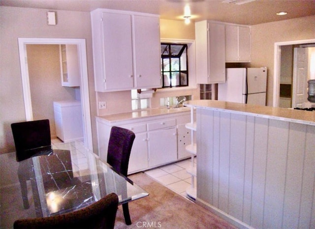 kitchen with white cabinetry, sink, white fridge, and light tile patterned floors