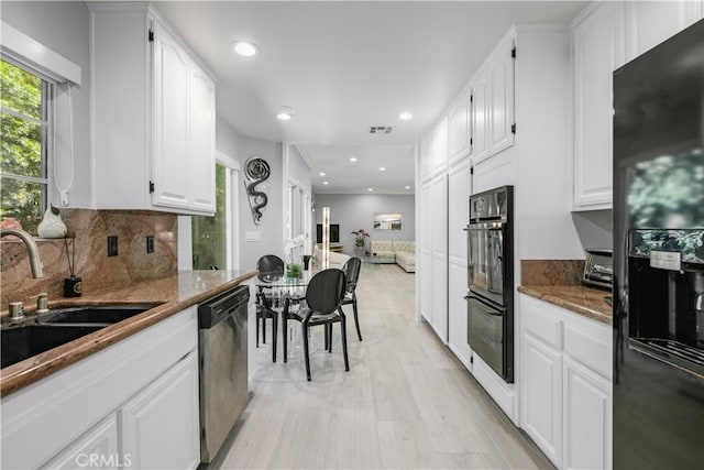 kitchen featuring decorative backsplash, sink, black appliances, light hardwood / wood-style flooring, and white cabinets