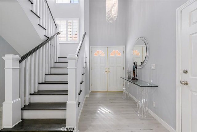 entryway featuring light wood-type flooring and a towering ceiling