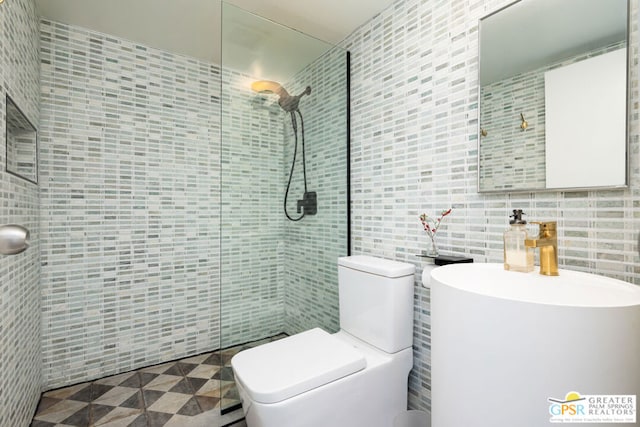 bathroom featuring a tile shower, toilet, and tile walls