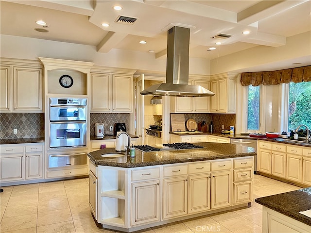 kitchen featuring an island with sink, island range hood, beamed ceiling, cream cabinetry, and sink