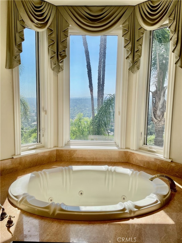 bathroom featuring tiled bath and a wealth of natural light