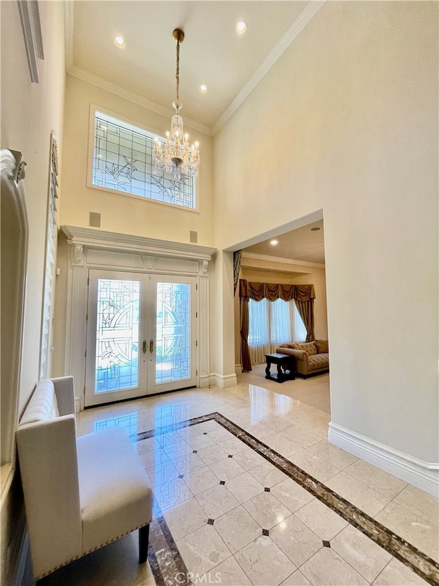 tiled foyer with a chandelier, ornamental molding, french doors, and a towering ceiling