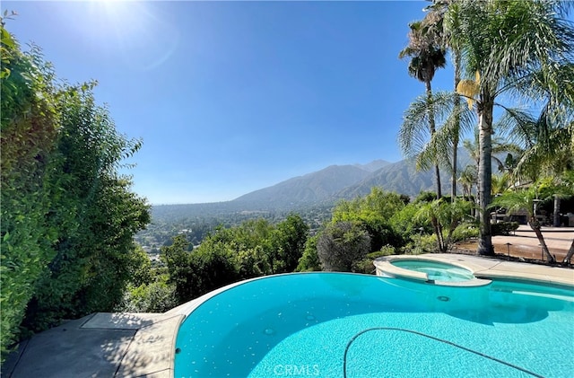 view of swimming pool with an in ground hot tub and a mountain view