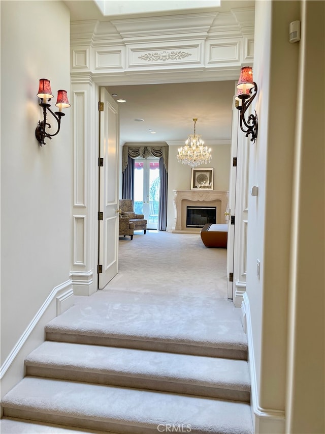 stairway with crown molding, carpet floors, and a chandelier