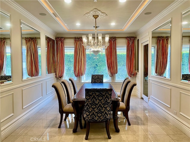 dining area featuring ornamental molding, light tile patterned flooring, a notable chandelier, and a raised ceiling