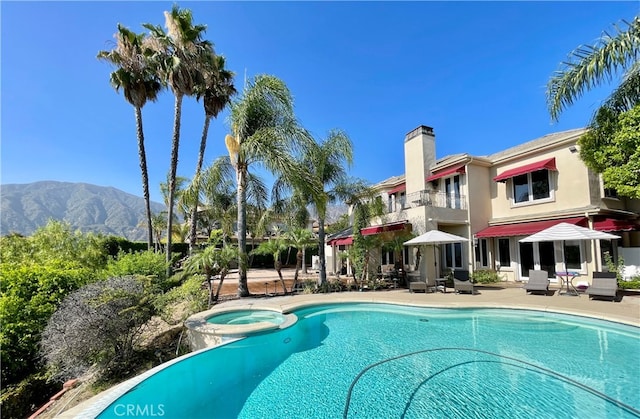 view of pool with an in ground hot tub, a mountain view, and a patio area