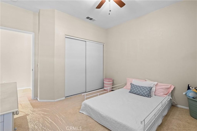 bedroom with ceiling fan, a closet, and light colored carpet