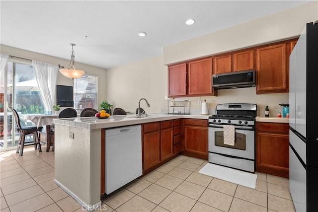 kitchen with kitchen peninsula, stainless steel appliances, sink, pendant lighting, and light tile patterned floors