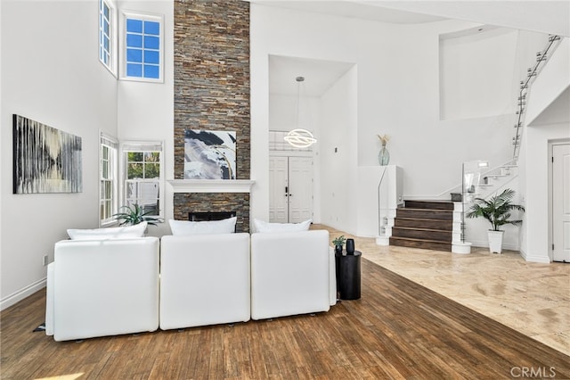 living room featuring a stone fireplace, hardwood / wood-style flooring, and a high ceiling