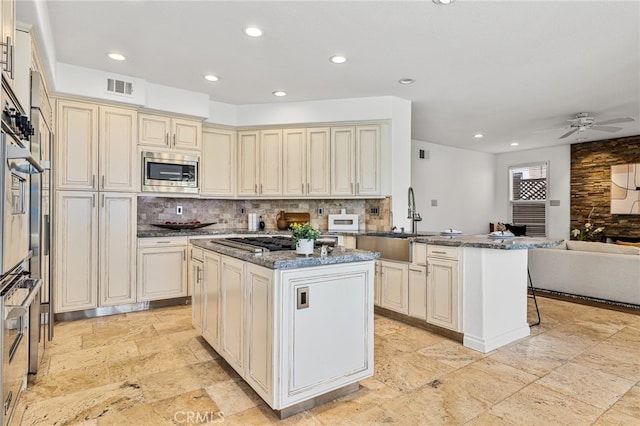 kitchen with cream cabinets, stainless steel appliances, kitchen peninsula, and a kitchen island