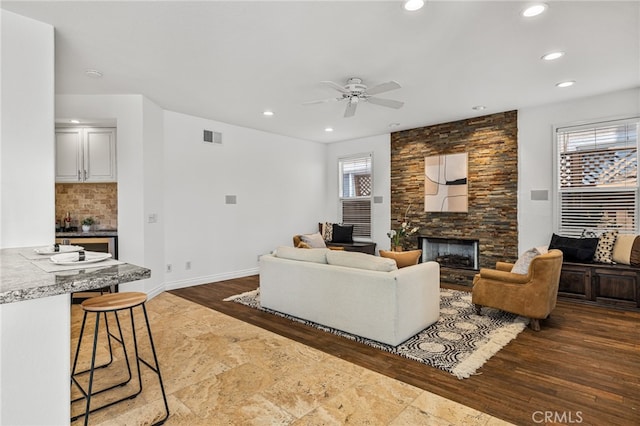 living room featuring a fireplace, dark hardwood / wood-style floors, ceiling fan, and a wealth of natural light