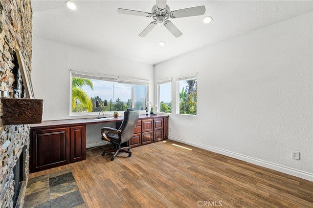 office space featuring wood-type flooring, built in desk, and ceiling fan