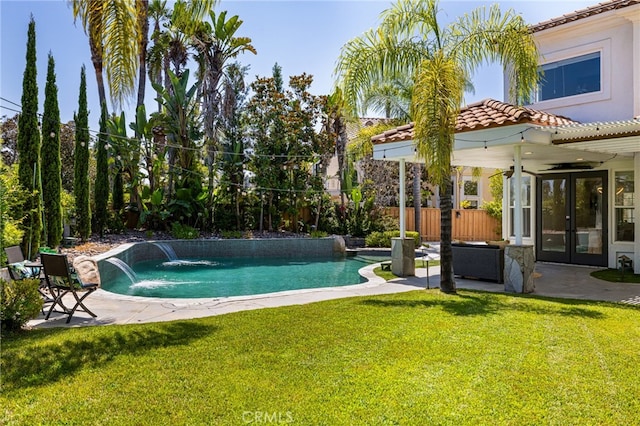 view of pool with pool water feature, a patio area, french doors, and a yard