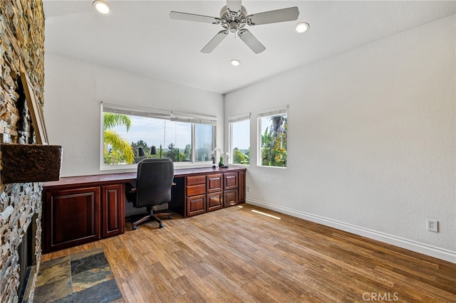 home office with light wood-type flooring, ceiling fan, and built in desk