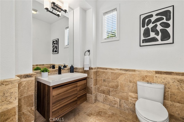 bathroom featuring vanity, tile walls, and toilet