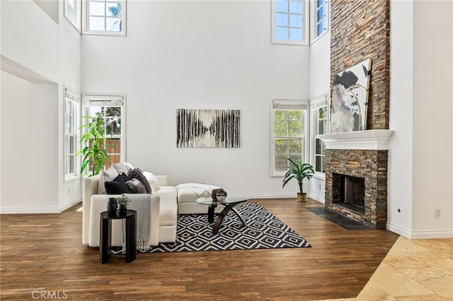 living room featuring a high ceiling, a fireplace, and dark wood-type flooring