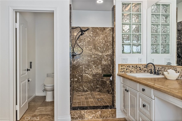 bathroom with tiled shower, vanity, and toilet