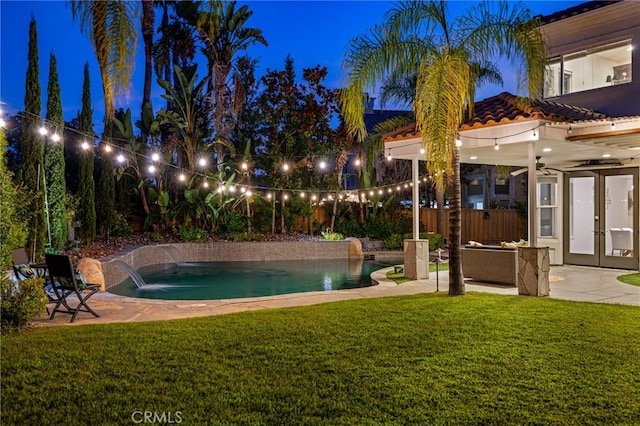 pool at twilight with a lawn, a patio, pool water feature, and french doors