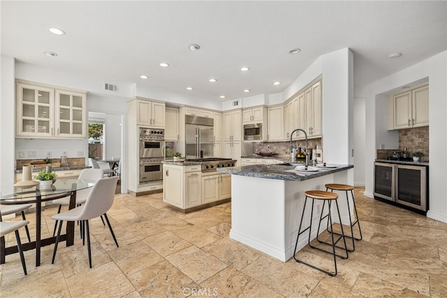 kitchen featuring a breakfast bar, a kitchen island, built in appliances, cream cabinets, and sink