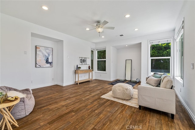 living room featuring ceiling fan, dark wood-type flooring, and a healthy amount of sunlight