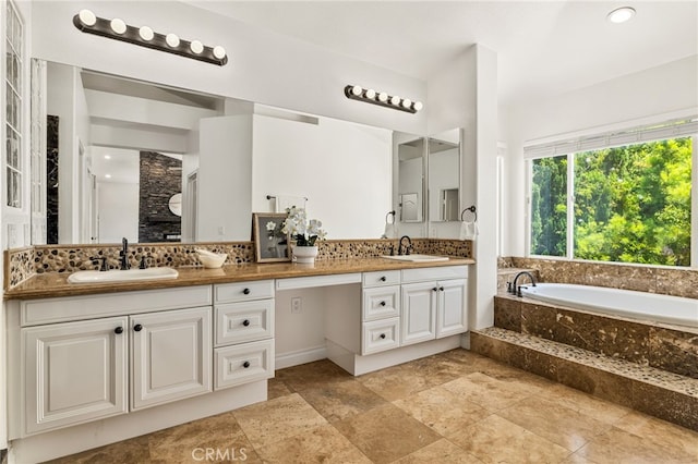 bathroom featuring a relaxing tiled tub and vanity