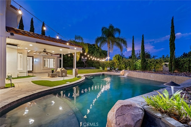 pool at dusk featuring outdoor lounge area, ceiling fan, and a patio area