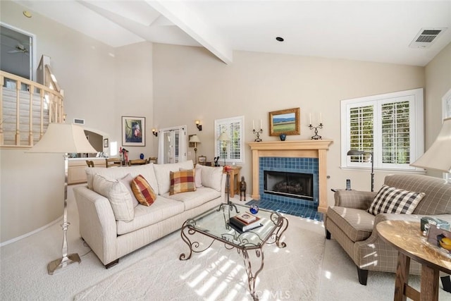 carpeted living room with lofted ceiling with beams and a tiled fireplace