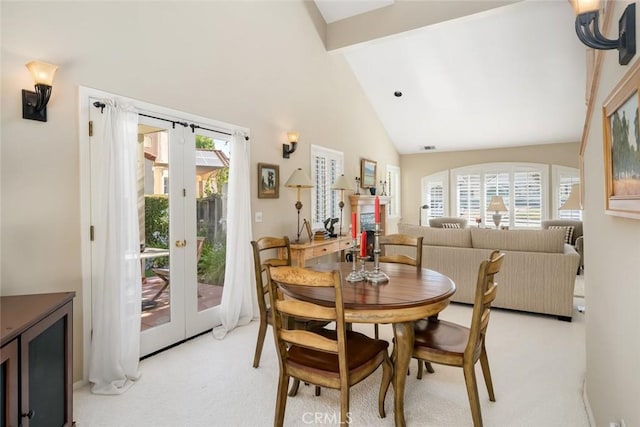 dining area with light carpet, french doors, high vaulted ceiling, and a healthy amount of sunlight