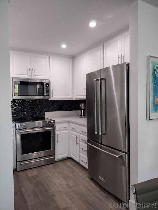 kitchen with backsplash, dark hardwood / wood-style floors, white cabinetry, and stainless steel appliances