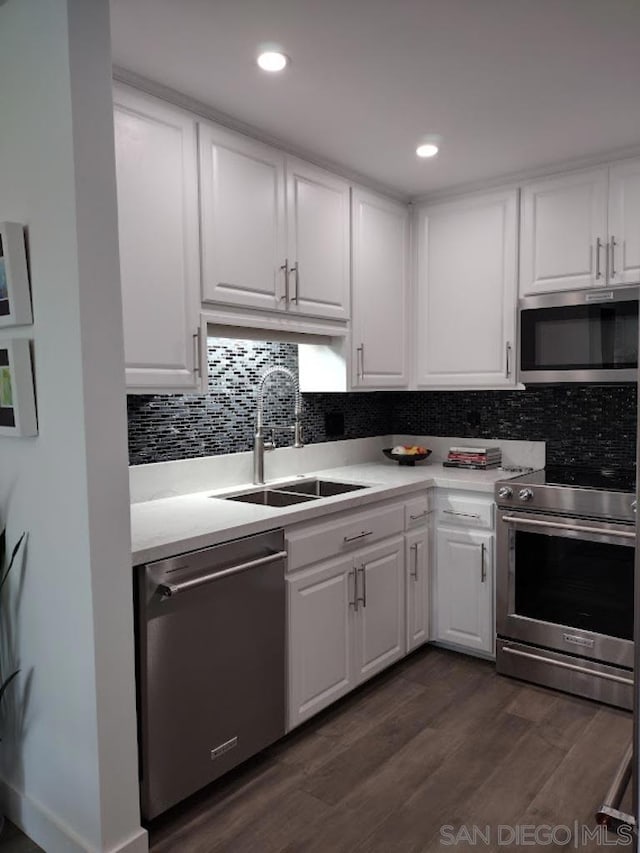 kitchen with sink, stainless steel appliances, tasteful backsplash, dark hardwood / wood-style flooring, and white cabinets