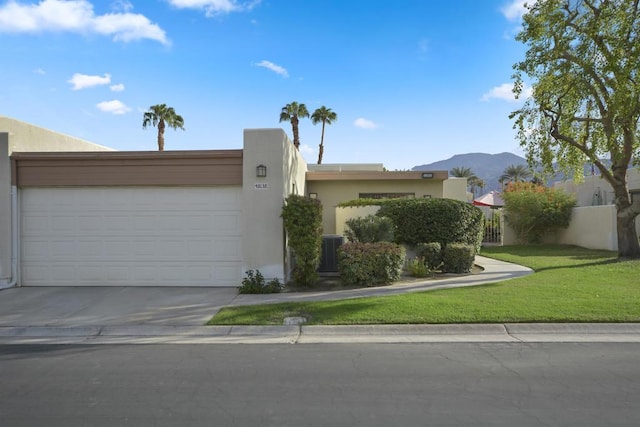 pueblo-style home with cooling unit, a garage, a mountain view, and a front yard