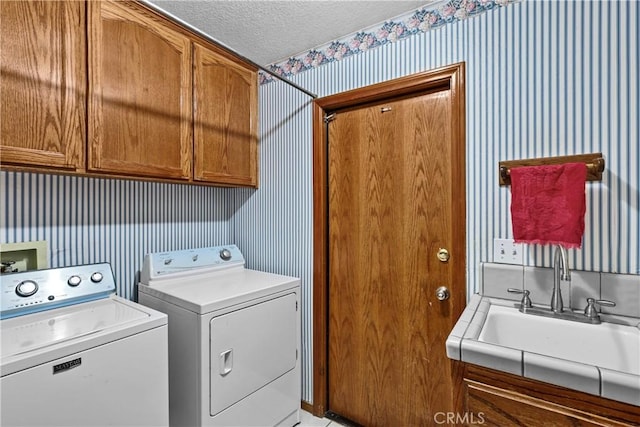 laundry room featuring cabinets, a textured ceiling, sink, and washing machine and clothes dryer