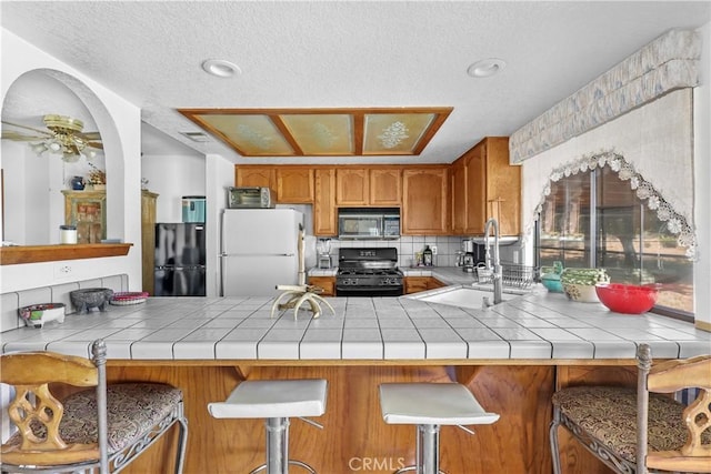 kitchen with black appliances, tile counters, and kitchen peninsula