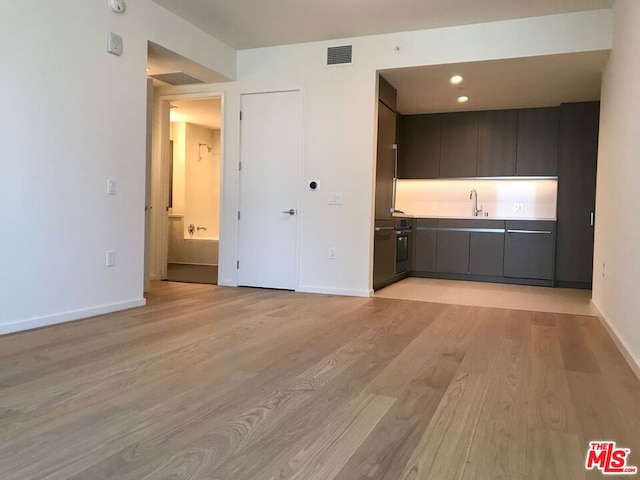 unfurnished living room featuring sink and light wood-type flooring