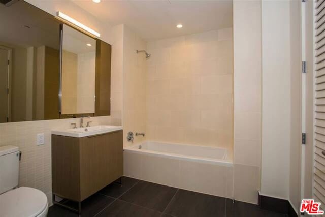 full bathroom with tiled shower / bath, vanity, toilet, and tile patterned floors