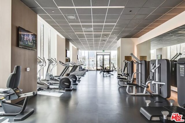 workout area featuring a paneled ceiling and a wall of windows