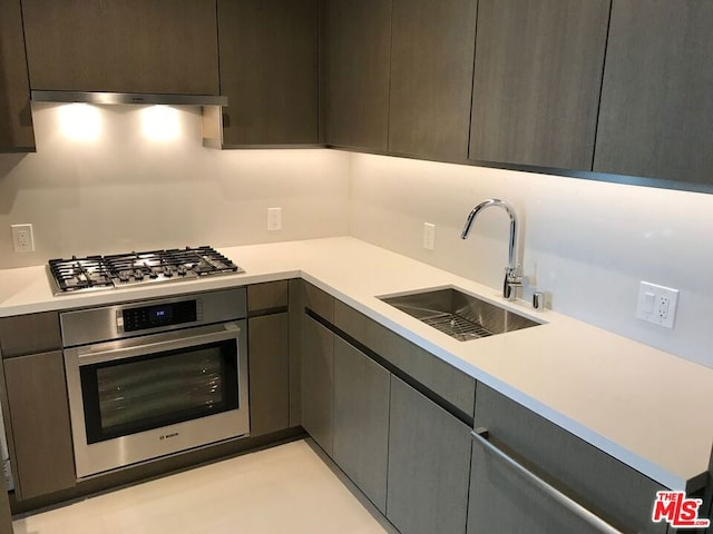 kitchen with appliances with stainless steel finishes, extractor fan, sink, and dark brown cabinets