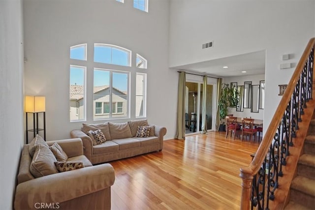 living room featuring a towering ceiling and wood-type flooring