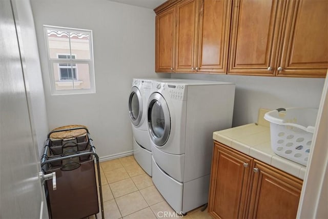 laundry area featuring cabinets, separate washer and dryer, and light tile patterned flooring