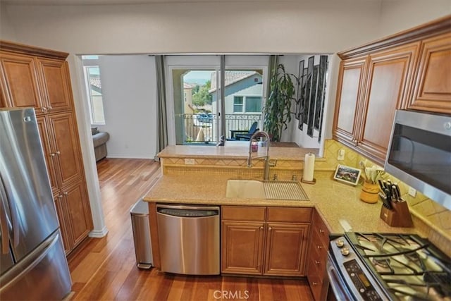 kitchen featuring kitchen peninsula, stainless steel appliances, dark wood-type flooring, and sink