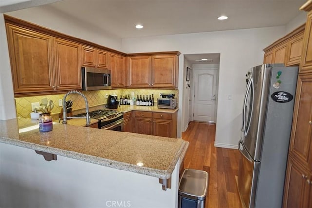 kitchen with a kitchen breakfast bar, kitchen peninsula, and appliances with stainless steel finishes