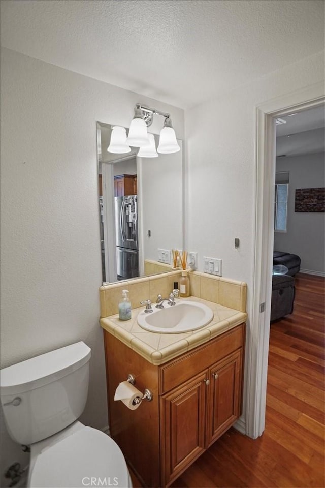 bathroom featuring toilet, vanity, a textured ceiling, and hardwood / wood-style flooring