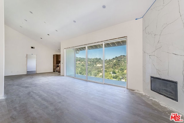 unfurnished living room with a fireplace and high vaulted ceiling