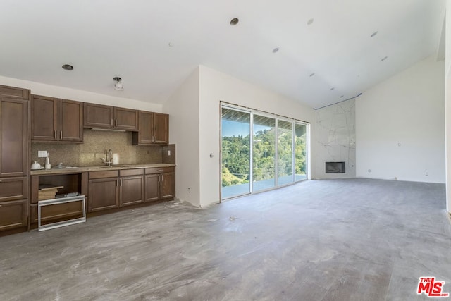 unfurnished living room with high vaulted ceiling, a premium fireplace, and sink