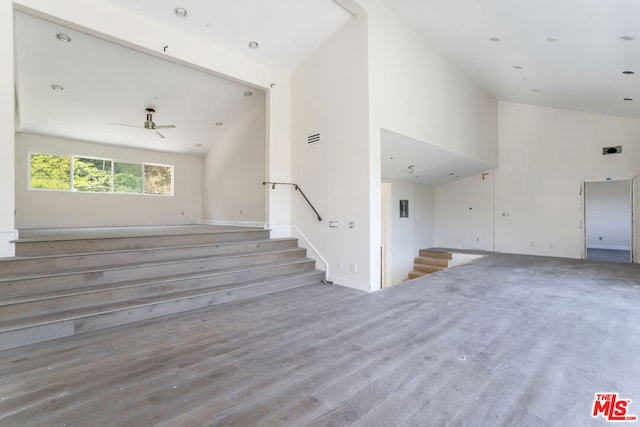 unfurnished living room featuring ceiling fan, wood-type flooring, and high vaulted ceiling